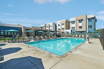 Resort style swimming pool with lounge chairs and umbrellas